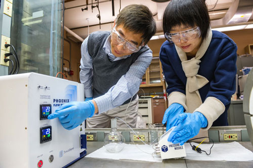 chemical engineer Jie Li, left, and postdoctoral researcher Alina Yan create coated nanoparticles in a continuous flow reactor