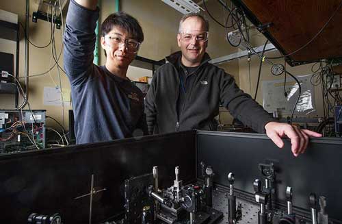 NREL scientists Ye Yang and Matt Beard stand in front of a transient absorption spectrometer in their laser lab