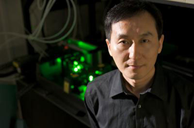 Chunlei Guo stands in front of his femtosecond laser, which can double the efficiency of a regular incandescent light bulb