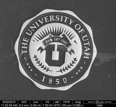 This electron microscope image shows a gilded University of Utah medallion