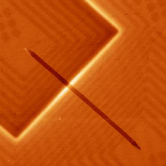 Magnetic force microscopy image of a racetrack made out of the magnetic alloy permalloy (dark brown) measured while writing a domain wall into the racetrack