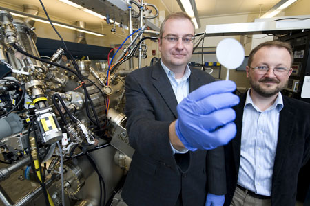 Purdue professors Michael Manfra, from left, and Gabor Csathy stand next to the high-mobility gallium-arsenide molecular beam epitaxy system at the Birck Nanotechnology Center