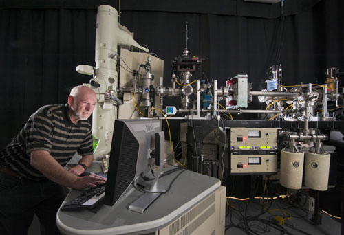 Daniel Buller stands in front of the beamline that connects the tandem accelerator to the transmission electron microscope (TEM) at Sandia's Ion Beam Laboratory