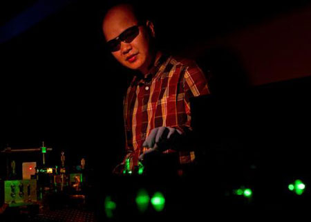 Cuong Dang manipulates a green beam that pumps the nanocrystals with energy, in this case producing red laser light
