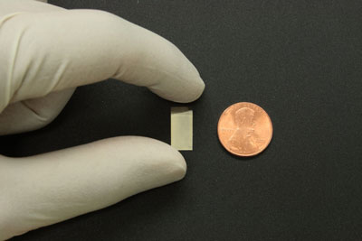 A silver nanoparticle mirror shown next to a penny for scale