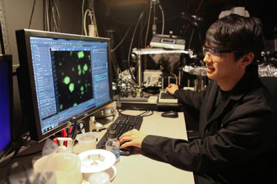 Graduate student Minyoung Kevin Kim views bacterial activity through a microscope