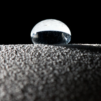 A droplet of water beads up on top of a hydrophobic surface. Water beads up even more on super-hydrophobic surfaces