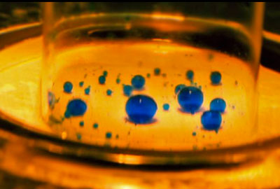 Tiny droplets of water, colored blue, are suspended in water