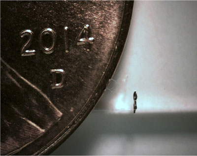 side view of a microrobot next to a U.S. penny