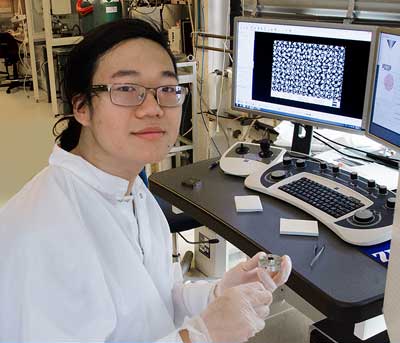 Justin Cheng holds an experimental sample of nanostructured gold on silicon