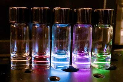 bottles glow in rainbow colors as laser causes nanoparticles suspended in cyclohexane to emit light