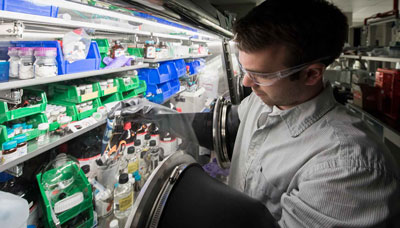 NREL researcher Dan Kroupa, working in a glove box, is performing ligand exchanges on PbS quantum dot samples