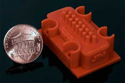 3D-printed manufacturing device in relation to size of a penny coin