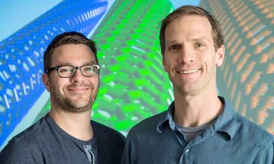 Two men stand in front of a screen that shows carbon nanotubes