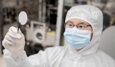 Working in a clean suit in the lab, Dr. Sun holds up a gallium-oxide template