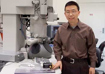 Xiaoli Tan is shown in the Ames Laboratory's Sensitive Instrument Facility with a special specimen holder, foreground, and a transmission electron microscope