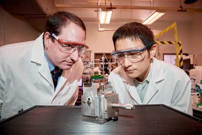 Michael Pettes, left, assistant professor of mechanical engineering, and Ph.D. student Wei Wu check a specially engineered device