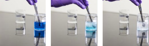 Researchers hold a small piece of the sponge-like material in water containing blue dye. After about 10 seconds, the water in the beaker turns clear