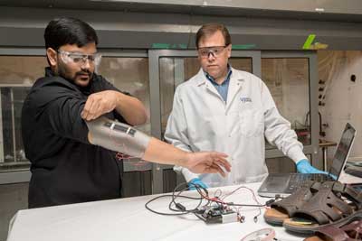 Sagar Doshi (left) and Erik Thostenson test an elbow sleeve outfitted with one of their novel sensors