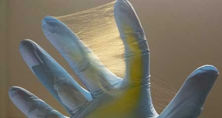 A gloved hand is covered in fine yellow  fibers
