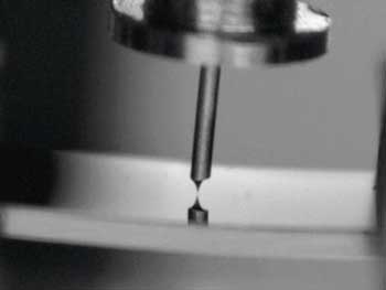 View into the scanning tunnelling microscope showing its metal tip very close to a surface under investigation