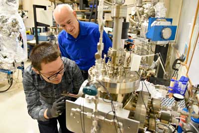 Postdoctoral researcher Gang Wang loads a sample into the system used to perform the nanotube crosslinking operation while Joseph Lyding looks on