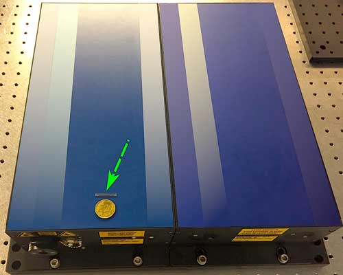 The green arrow points to a chip that can be equipped with up to ten femtosecond lasers. The blue box on which it rests, on the other hand, is a single conventional laser