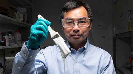Xiulin Ruan, a Purdue University professor of mechanical engineering holds a brush with ultrawhite paint