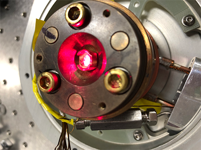 A strong laser is seen illuminating a material in a low-temperature chamber