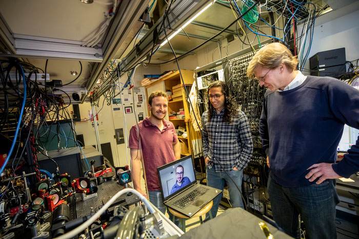 Dolev Bluvstein, Harry Levine (on the laptop), Sepehr Ebadi and Mikhail Lukin, on right, standing next to their neutral atom quantum computer, on left
