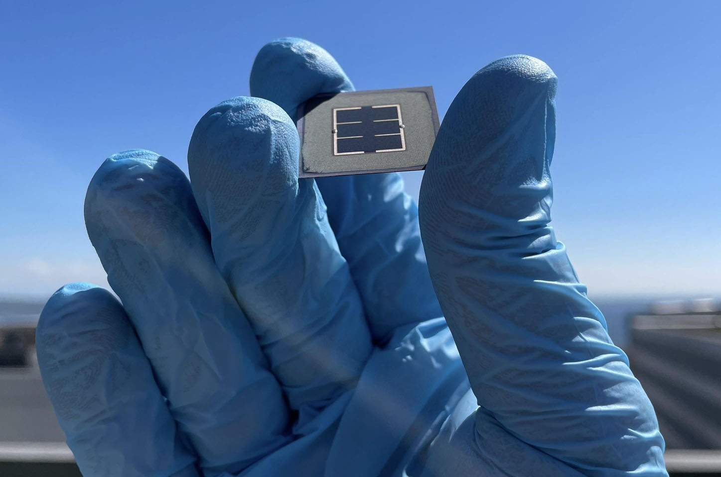 blue gloved hand holding solar cell