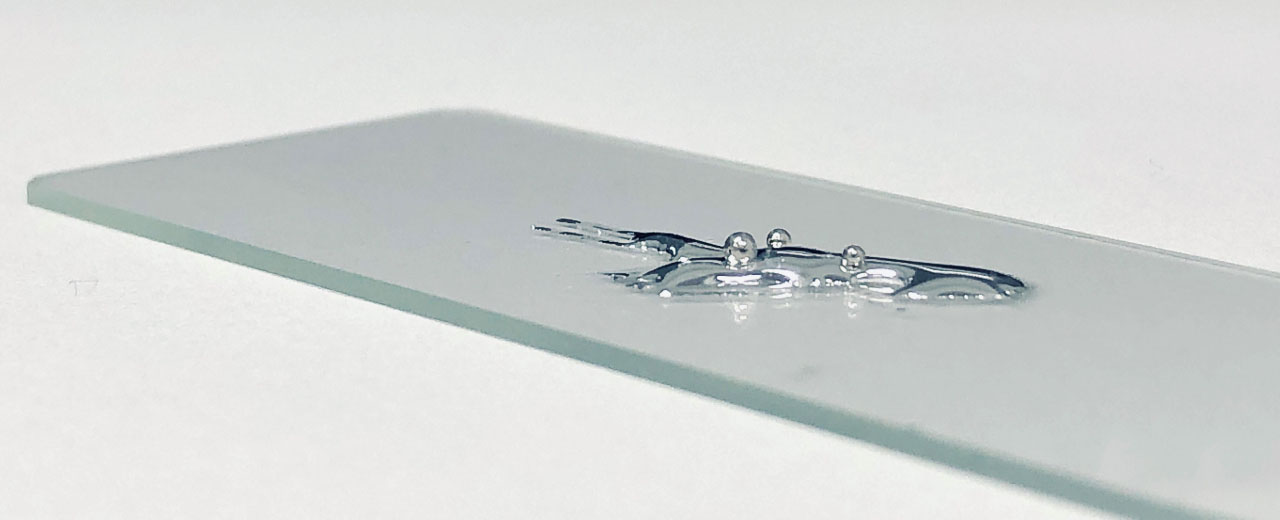 Liquid gallium and three solid beads of platinum, demonstrating the dissolution process of platinum in gallium