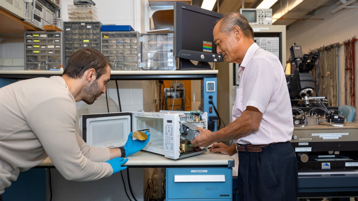 James Hwang, research professor in the Department of Materials Science and Engineering, right, at his modified microwave with Gianluca Fabi holding a semiconductor at left