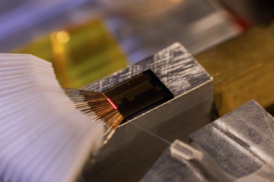 Laser light glows on the surface of a photonics chip