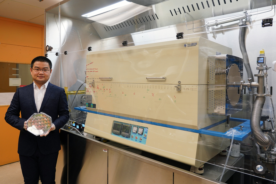 Graduate student Jiadi Zhu holding an 8-inch CMOS wafer with molybdenum disulfide thin film