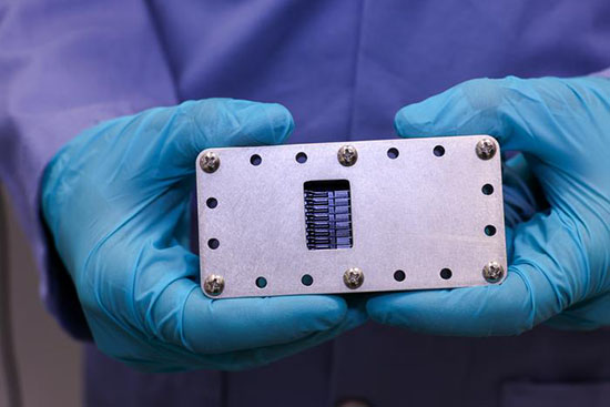  tubes carrying different LNP components feed into a glass microfluidic chip encased in aluminum housing