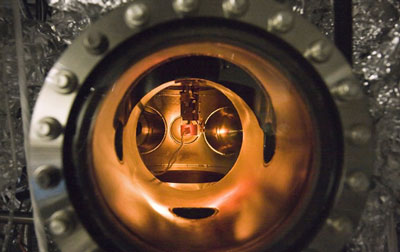 A small PETE device made with cesium-coated gallium nitride glows while being tested inside an ultra-high vacuum chamber. The tests proved that the process simultaneously converted light and heat energy into electrical current