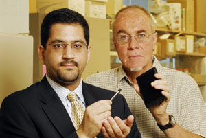 Associate professor Muhannad Bakir (left), from Georgia Tech's School of Electrical and Computer Engineering, holds a prototype electronic microplate, while Professor John McDonald, from the School of Biology, holds an example of the conventional microplate