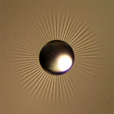 A starburst of wrinkles form in a thin film material