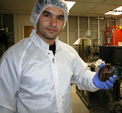 SDSU assistant professor Mahdi Farrokh Baroughi’s face is reflected from the surface of a third-generation solar cell