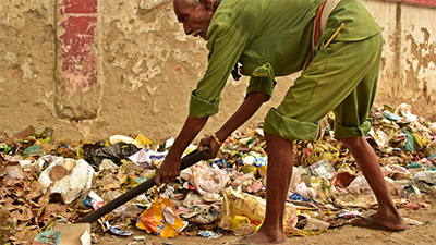 Indian man shovelling trash