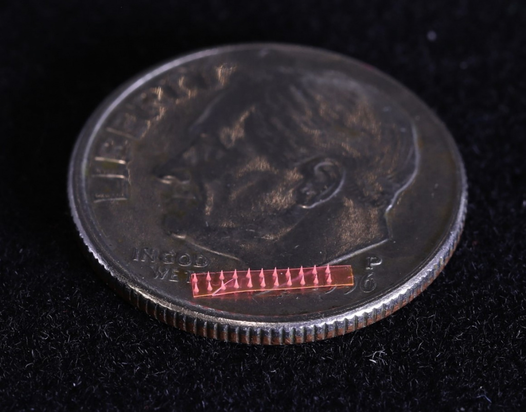 Illustration of a silk microneedle array on a dime coin