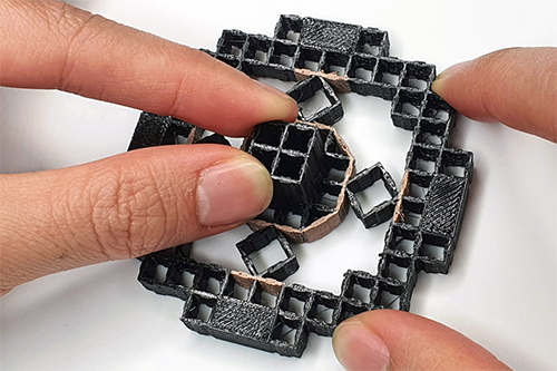 fingers holding a 3D-printed structure