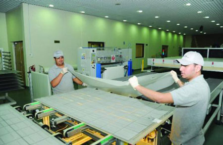 Workers handling solar panels in the KACST solar panel manufacturing plant