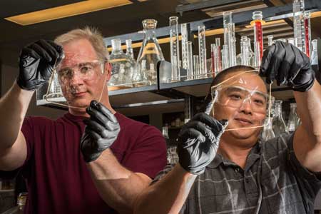 Sandia National Laboratories researchers Cy Fujimoto, right, and Michael Hibbs demonstrate the clarity of their recent membranes
