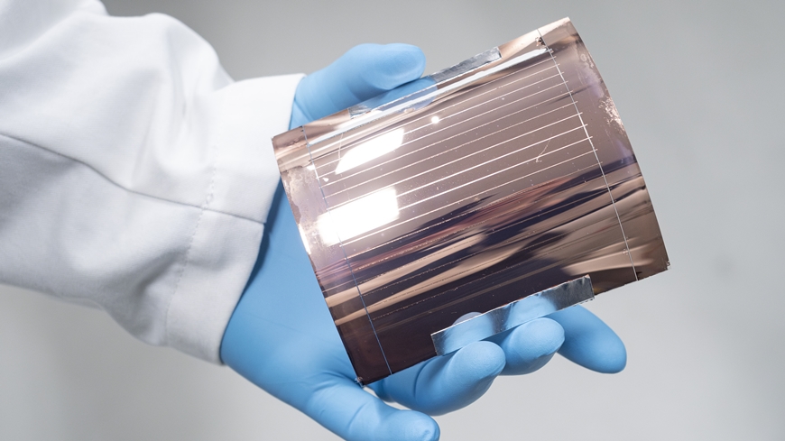 gloved hand holding a two-layer perovskite solar cell