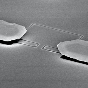 A scanning electron microscope image of a microchannel device that squeezes electron crystals on the surface of liquid helium through a narrow bottleneck