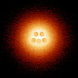 An artificial atomic nucleus made up of five charged calcium dimers is centered in an atomic-collapse electron cloud