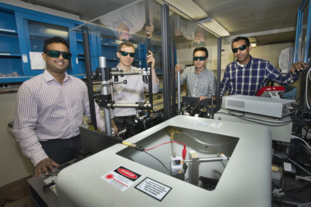 Nanditha Dissanayake, Matthew Eisaman, Yutong Pang, and Ahsan Ashraf display the setup used to track the flow of electrons through the photoactive layer of organic solar cells