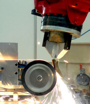 A robot automatically restores the damaged sections of a turbine blade at a grinding station